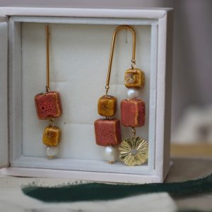Pendientes asimétricos con piezas de cerámica color mostaza y rosa y perlas naturales.